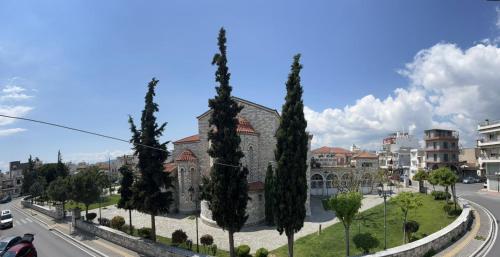 eine Reihe von Zypressen vor einem Gebäude in der Unterkunft Hotel Anastasia in Volos