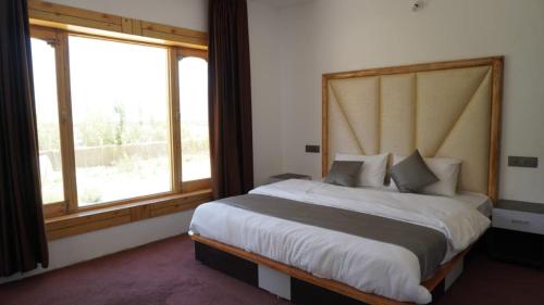 a bedroom with a large bed with a large window at Natures View Residency in Hundar