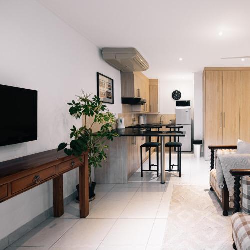 uma cozinha e sala de estar com uma mesa e uma televisão em Poolside Cottage em Joanesburgo