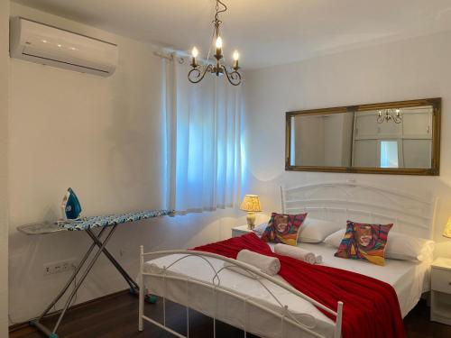 een slaapkamer met een bed met een rode deken en een spiegel bij Apartments Villa ALEN in Mimice
