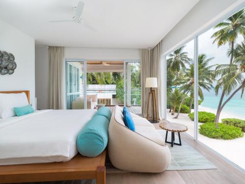 a bedroom with a bed and a view of the ocean at Amilla Maldives in Kihaadhoo