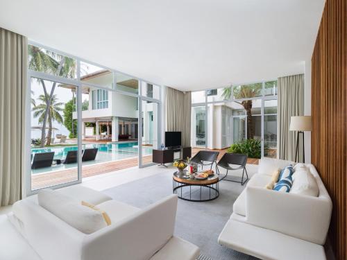 a living room with white furniture and a pool at Amilla Maldives in Kihaadhoo
