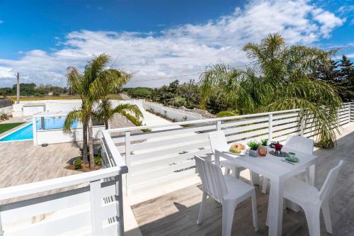een witte tafel en stoelen op het balkon van een huis bij Amurusu Residence in Punta Secca