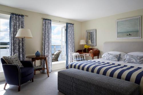 a bedroom with a bed and a chair and a window at Hotel Tresanton in Saint Mawes