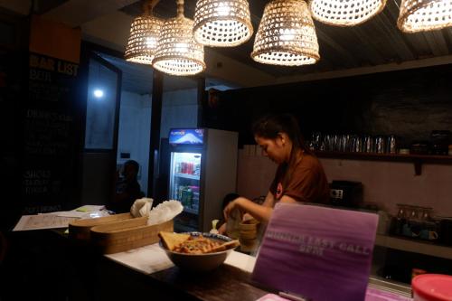 a woman standing at a counter in a restaurant preparing food at Lexias Hostel and Workspace - Siargao in Catagnan