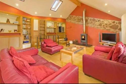 uma sala de estar com mobiliário vermelho e uma televisão em Mill Cottage Garden Annexe em Newton Abbot