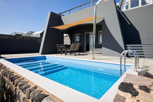 a swimming pool in front of a house at Theano Cave Suites & Villas in Imerovigli