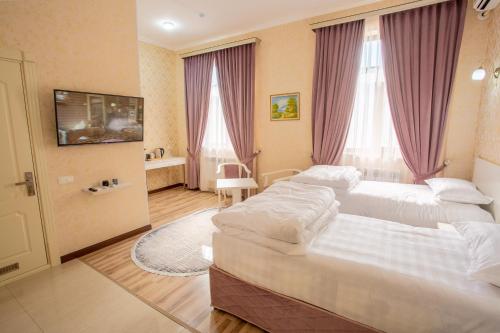 een hotelkamer met 2 bedden en een televisie bij Muxlis Hotel in Tasjkent