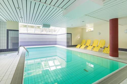 une grande piscine avec des chaises jaunes dans un bâtiment dans l'établissement Villa a cappella A6, à Binz