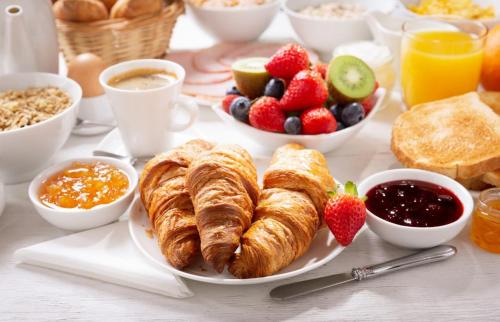 un tavolo per la colazione con croissant, frutta e altri prodotti per la colazione di B&B I TRE GATTI a Pesaro
