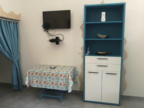 une armoire bleue et blanche avec une table et une télévision dans l'établissement Elis...land..., à Torre Canne