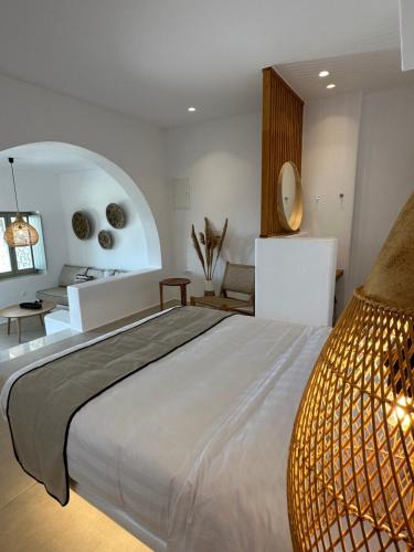 Quattro Venti Suites Mykonos في تورلوس: غرفة نوم بسرير ابيض كبير وطاولة