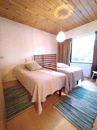 a bedroom with two beds and a large window at Punkaharju Savonlinna, perheasunto, Family home in Savonlinna