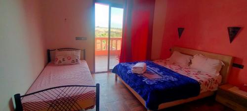 1 dormitorio con 2 camas y ventana en chez JM saida, en Ourika