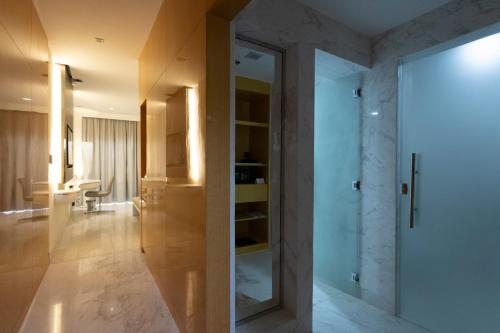 アル・アインにあるAlberni Jabal Hafeet Hotel Al Ainのガラスドア付きのバスルーム、デスクが備わります。