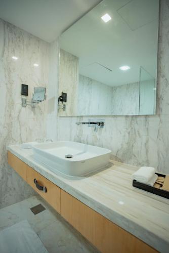 a white bathroom with a sink and a mirror at Alberni Jabal Hafeet Hotel Al Ain in Al Ain