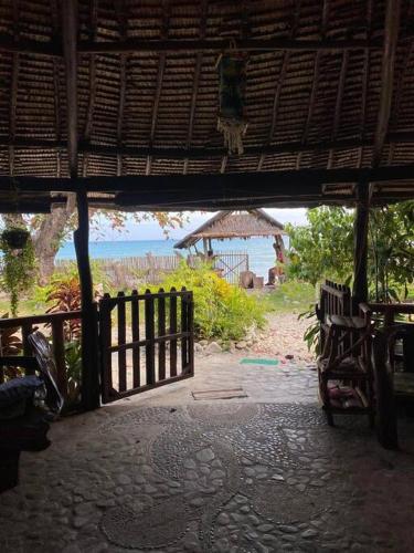 ein offenes Tor zu einem Strand mit einem Zaun in der Unterkunft Auntie Mina's Beach Cabins in Puerto Princesa