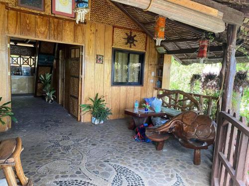 eine Veranda eines Hauses mit einem Tisch und Stühlen in der Unterkunft Auntie Mina's Beach Cabins in Puerto Princesa
