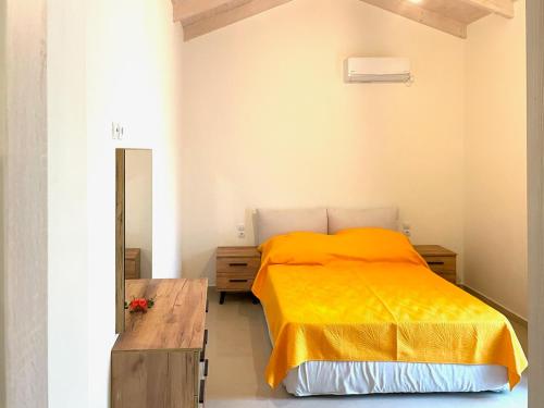 a bedroom with a bed with a yellow blanket at Lefkada house with private yard parking 2 in Nydri