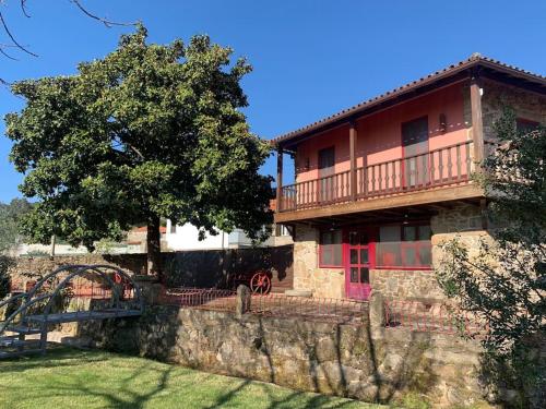 a large house with a tree and a stone wall at Casa do Palheiro - Valença in Bade