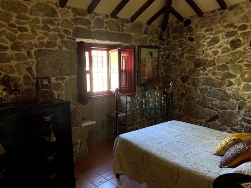 a bedroom with a bed and a stone wall at Casa do Palheiro, Bade, Cerdal. in Bade