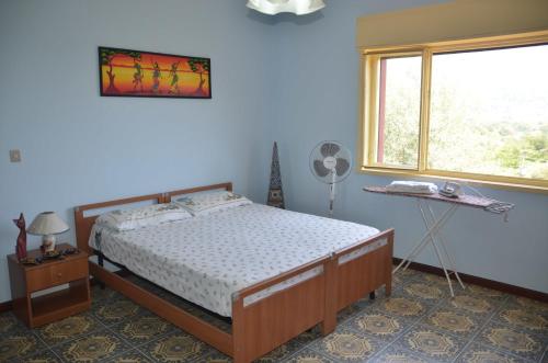 a bedroom with a bed and a window and a fan at Gole Dell'Alcantara Villa Lucia in Motta Camastra