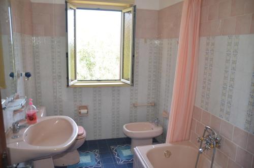 Motta CamastraにあるGole Dell'Alcantara Villa Luciaのバスルーム(洗面台2台、トイレ付)、窓が備わります。