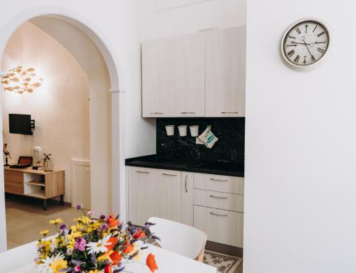 a kitchen with white cabinets and a clock on the wall at Mare Adesso in Polignano a Mare