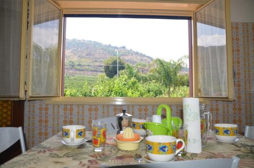 a kitchen counter with a table with cups and a window at Gole Dell'Alcantara Villa Lucia in Motta Camastra