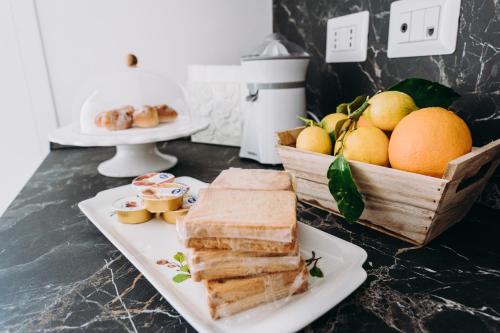a white plate with sandwiches and a basket of fruit at Mare Adesso in Polignano a Mare