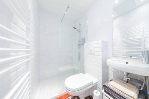 La salle de bains blanche est pourvue de toilettes et d'un lavabo. dans l'établissement Sacré Petit Studio in the Coeur of Montmartre, à Paris