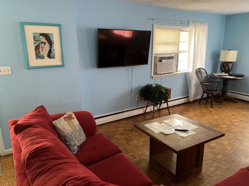 a living room with a red couch and a table at Beach Front on the Bay in our Rustic, Pet Friendly Cottage home in North Camellia Acres