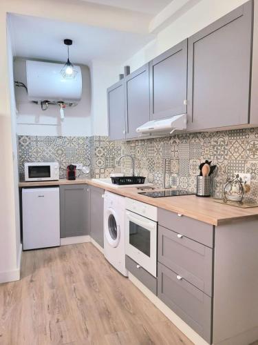 une cuisine avec des armoires blanches et une laveuse et une sécheuse dans l'établissement Chez Mélanie et Rodolphe, à La Ciotat