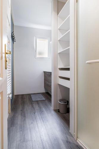 un couloir avec des étagères blanches et une chambre dotée de parquet. dans l'établissement Le 17BIS, à La Chevrolière