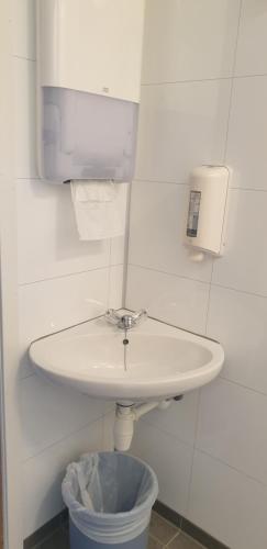 een witte wastafel in een badkamer met een vuilnisbak bij Bøyum Camping in Fjarland