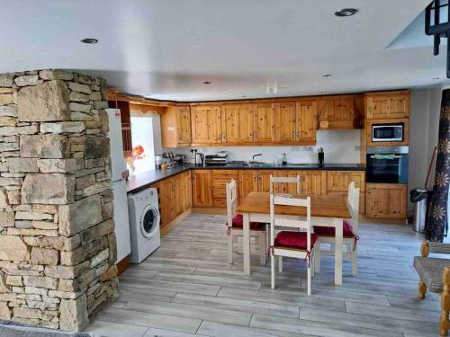 cocina con mesa y pared de piedra en Eanymore Farm Cottage, en Donegal