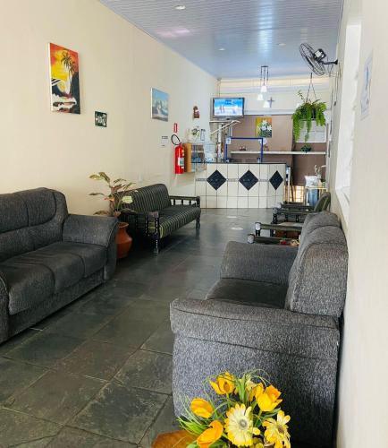 a living room with couches and a table with flowers at Hotel Planalto in Poços de Caldas