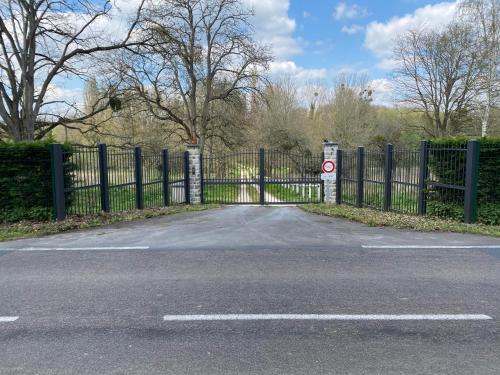 a gate to a driveway with a fence at Le Moulin Bleu in Saint Cyr-sous-Dourdan