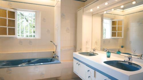 une salle de bain avec deux lavabos et un grand miroir dans l'établissement Villa Bois Romay dans le Luberon avec piscine, tennis et pétanque., à La Bastide-des-Jourdans