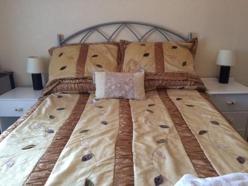 a bed with a blanket and pillows on it at Ardgarry Holiday House in Inverness