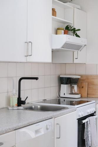 a kitchen with white cabinets and a sink at Strandfogedgården in Ulfborg