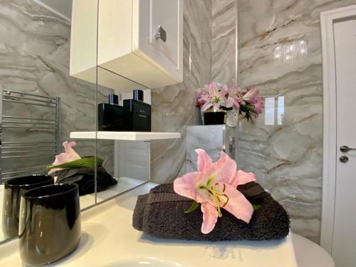 un bagno con lavandino e ripiano con fiori rosa di Luxury Apartament & Parking a Floreşti