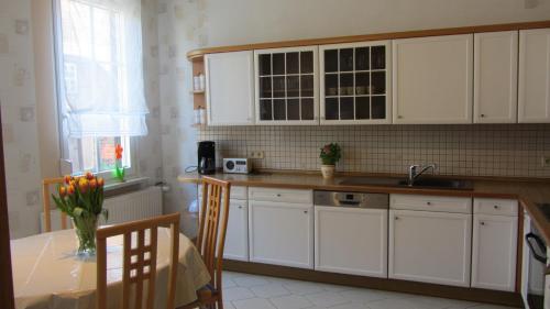eine Küche mit weißen Schränken, einem Tisch und einem Waschbecken in der Unterkunft Ferienwohnung am Drömling Südheide - Gerda in Bergfeld