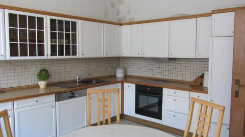 una cocina blanca con armarios blancos y fregadero en Ferienwohnung am Drömling Südheide - Gerda, en Bergfeld