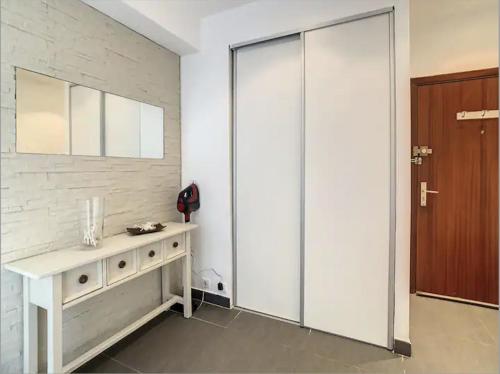 une chambre blanche avec une porte coulissante en verre et une table dans l'établissement Superbe Appartement 2p avec place de parking, à Antibes