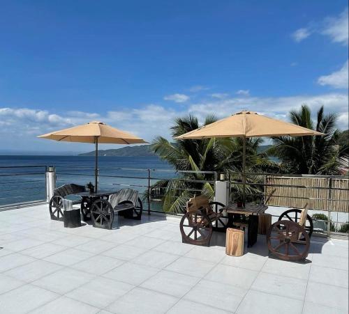 a patio with tables and umbrellas and the ocean at The Philip Ann Resort in Mabini