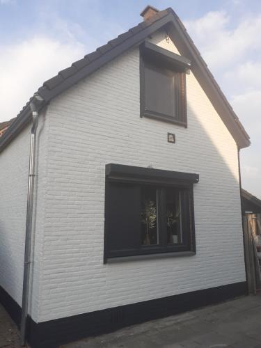 a white house with a window on the side of it at huisje in zeeland helemaal gerenoveerd in Sint Annaland