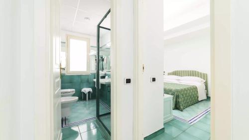 bagno con letto, lavandino e specchio di Hotel Santa Caterina a Palinuro