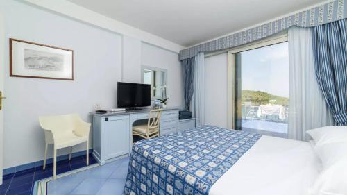 ein Hotelzimmer mit einem Bett, einem Schreibtisch und einem Fenster in der Unterkunft Hotel Santa Caterina in Palinuro