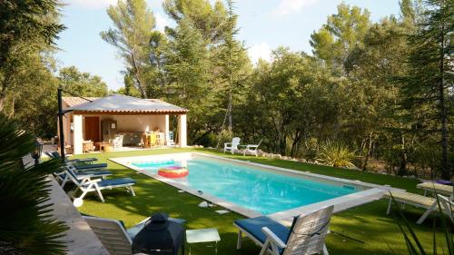 une piscine avec des chaises et un gazebo dans l'établissement Villa Bois Romay dans le Luberon avec piscine, tennis et pétanque., à La Bastide-des-Jourdans